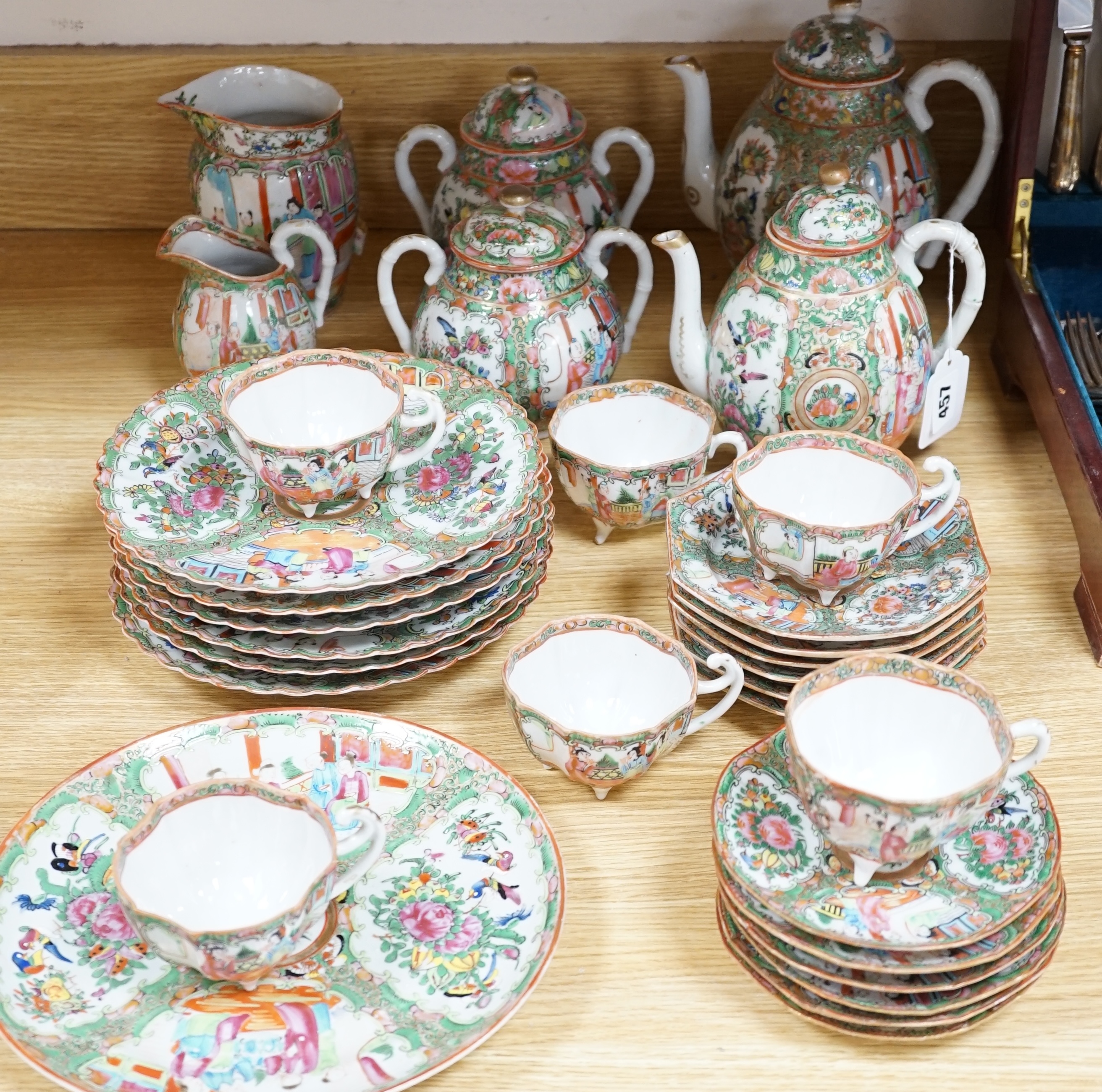 A Chinese famille rose six place setting tea service, including a large tea pot and cover, a smaller water pot and cover, two sugar bowls with covers, a large milk jug (handle broken) a small cream jug and a cake plate,(